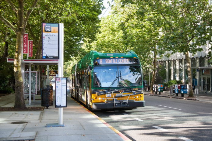 A photo of a King County Metro bus pulling into a bus station on a tree-lined street.