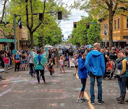 Olympia Enacts Targeted Citywide Missing Middle Housing Reform, Using GMA and SEPA ‘Safe Harbor’ People throng the street closed for a festival.