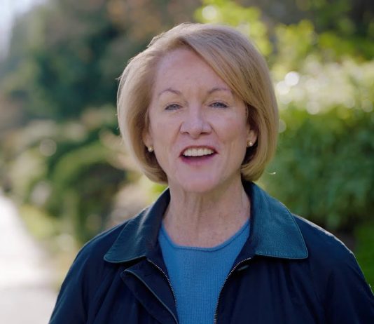 Durkan Text Scandal Whistleblowers Sue City for Retaliation Mayor Durkan stands on a sidewalk on a leafy residential block.