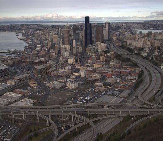 It’s a Car Car World–We Just Live in It A birds eye view of Downtown Seattle from the south with the I-5 and I-90 spaghetti interchange dominating the frame.