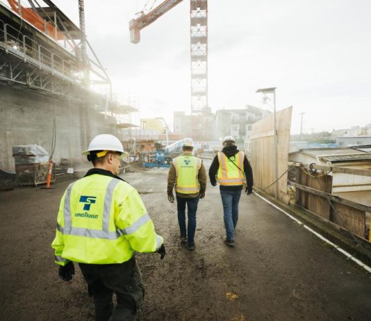 Seattle Subway-Backed HB 1304 Gets First Hearing February 9th Three construction workers in Sound Transit vests walk a construction site with crane overhead.