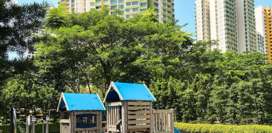 A playground with trees and public housing towers in the background
