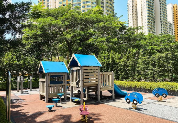 A playground with trees and public housing towers in the background