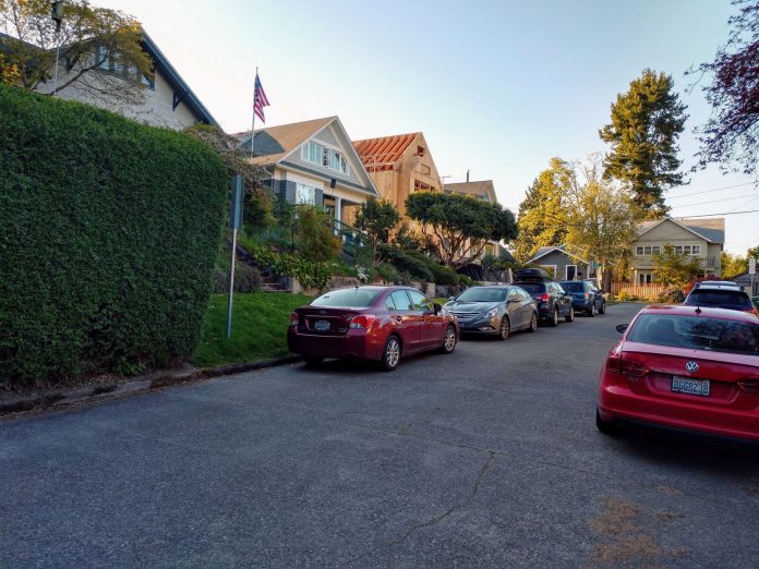 A street with a row of single family homes with one under construction.