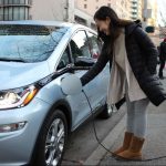 Women charing electric car by Puget Sound Clean Air Agency