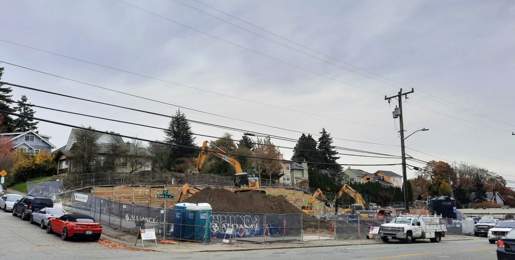 Four backhoes and excavators work in a pile of dirt at the corner of Stone Way and N 42nd Street.