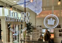 The New Bootleg Brand Uncovering the Best of Seattle’s Historic Iconography Chinatown street reflects in the window of the popup store where Nate and Ryan lean on a counter near their merch.