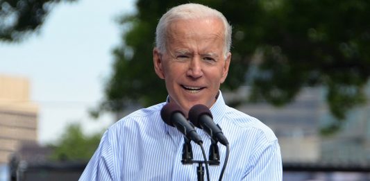 Joe Biden in a blue collar behind a lectern with Biden for President on it.