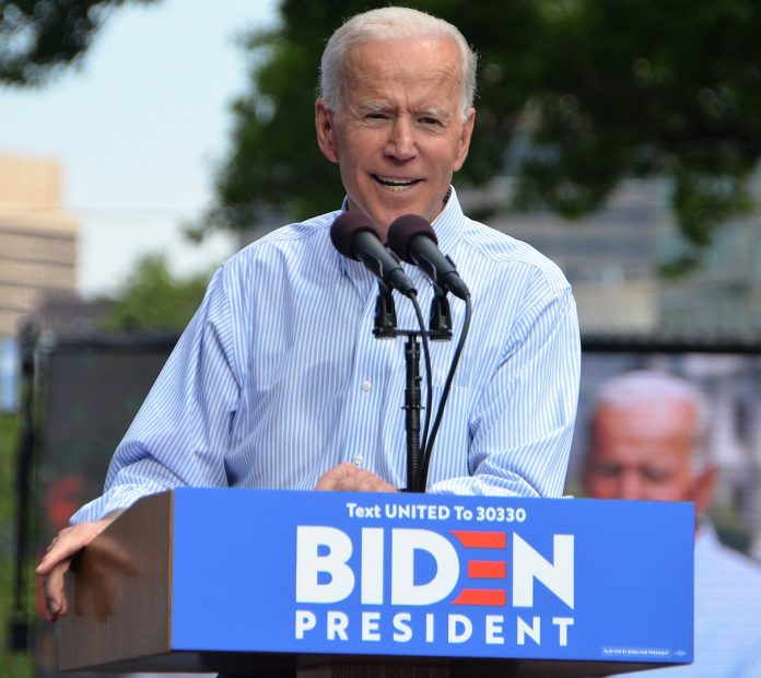 Joe Biden in a blue collar behind a lectern with Biden for President on it.