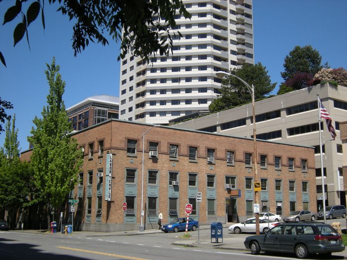 The three story brick labor temple with teal accents. A Belltown skyscraper is in the background.