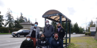 A woman in a wheelchair and five other advocates at a Tacoma bus stop.