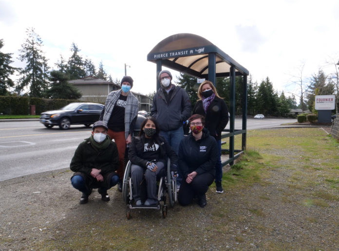 A woman in a wheelchair and five other advocates at a Tacoma bus stop.