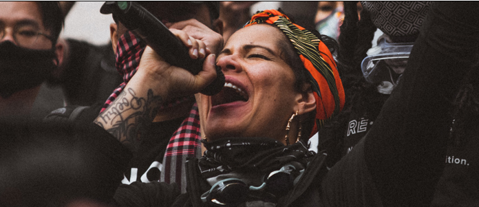 Nikkita Oliver projecting into a microphone.