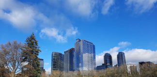Parkgoes sit on the ampitheater at Bellevue's Downtown park with skyscrapers in the background.
