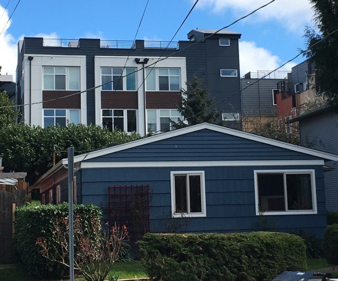 Photo of a single-story duplex in Wallingford, with three-story townhomes behind it.