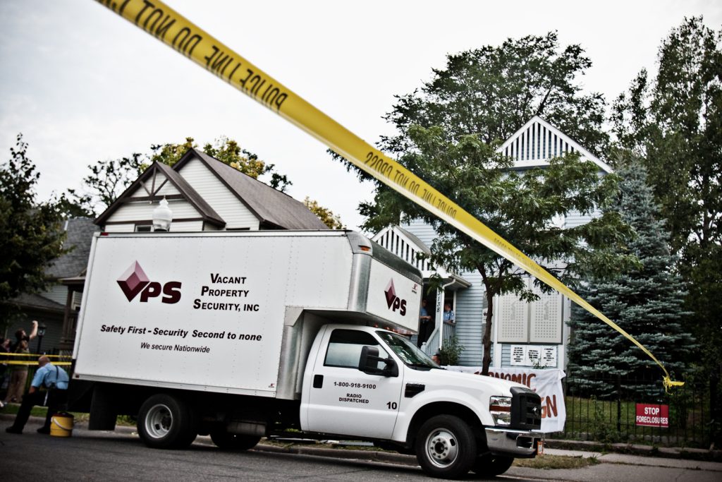 Yellow police tape and a moving truck outside a home being evicted.