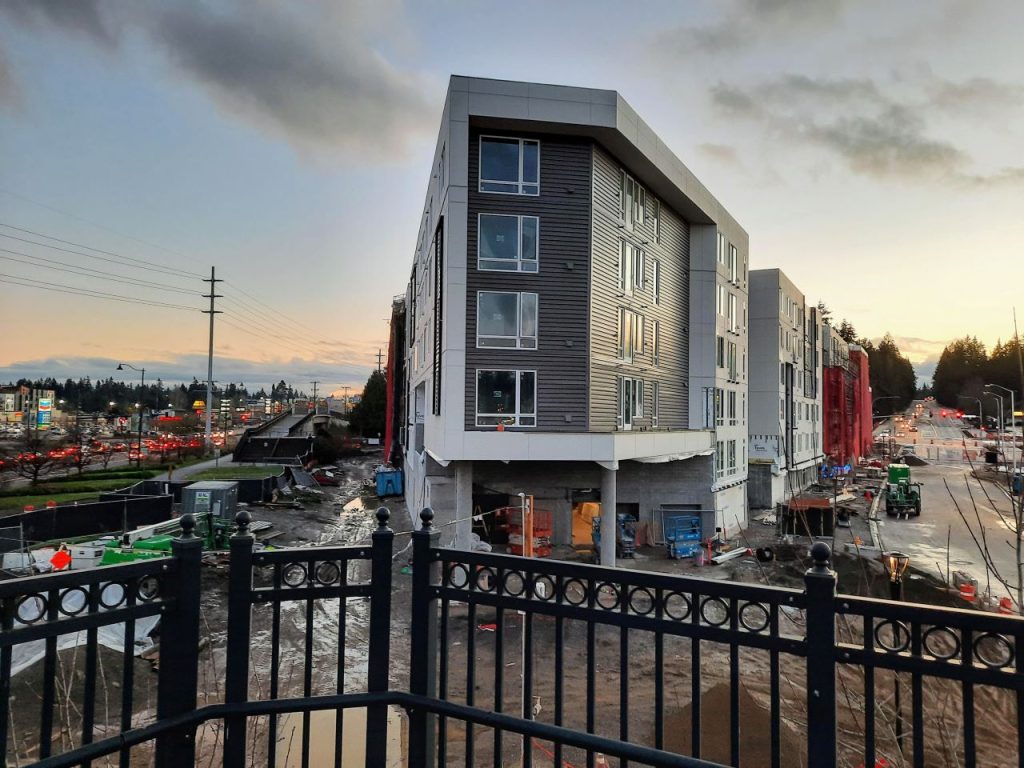 A new triangular shaped six-story apartment building at dusk.