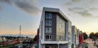 A new triangular shaped six-story apartment building at dusk.