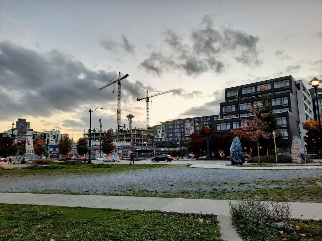 Three tower cranes and Space Needle stand in the distance looking west from Lake Union Park.