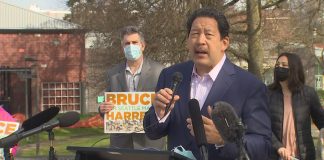 Bruce Harrell in a suitcoast with a microphone in hand at his candidacy announcement press conference.