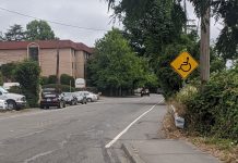 Op-ed: Why We Can’t Support a Transportation Package that Leaves Us Behind A yellow sign with a wheelchair on it indicates the people rolling are to use the gutter after the sidewalk ends. They did paint a stripe along the gutter at least.