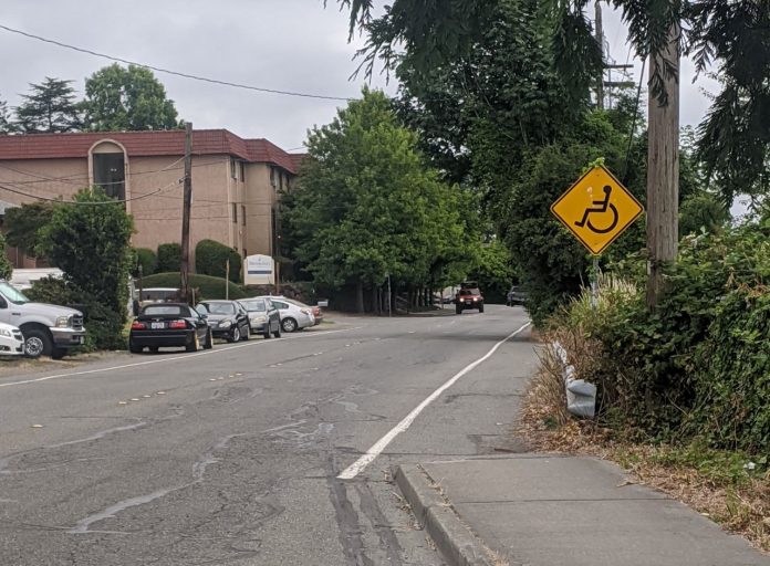 A yellow sign with a wheelchair on it indicates the people rolling are to use the gutter after the sidewalk ends. They did paint a stripe along the gutter at least.