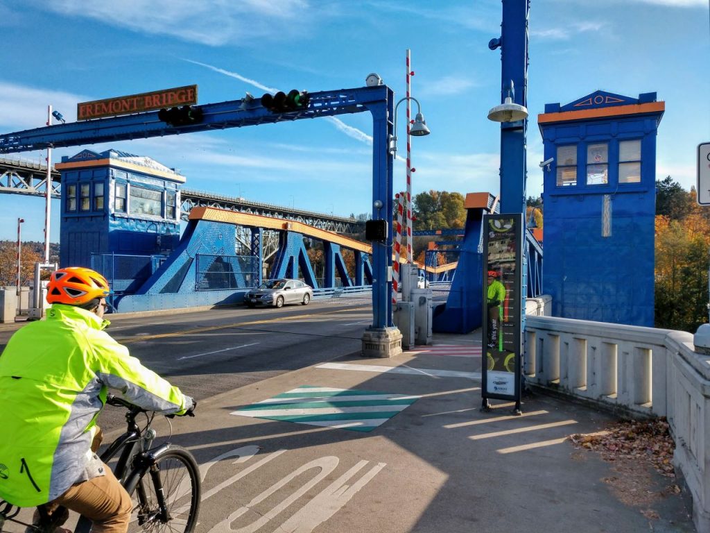 A rider in casual clothes but a high visibility jacket bikes toward the Fremont Bridge