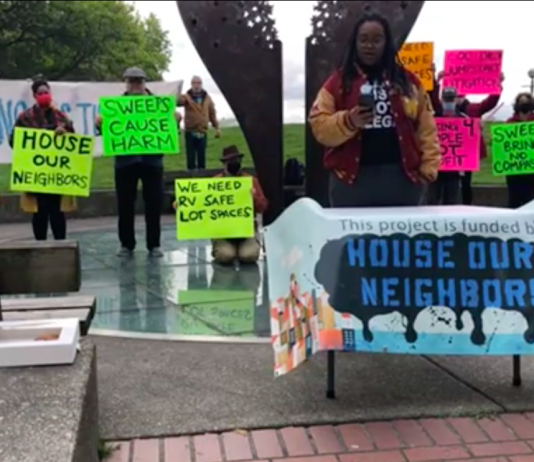 Judge Strikes ‘Compassion Seattle’ City Charter Amendment from November Ballot – Update A photograph showing participants holding colorful signs at a press event. The signs carry messages such as "sweeps cause harm" and "sweeps bring no compassion"