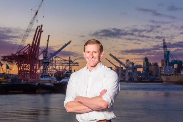 Ryan calkins stands in front of cranes on the Seattle waterfront.