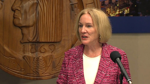 Mayor Durkan stands in front of the City seal.