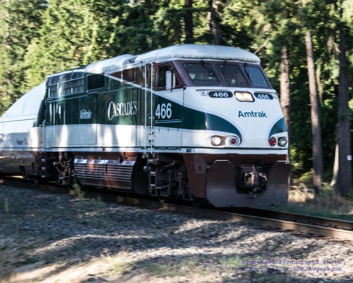 A photo of an Amtrak Cascades locomotive car surrounded by forest.