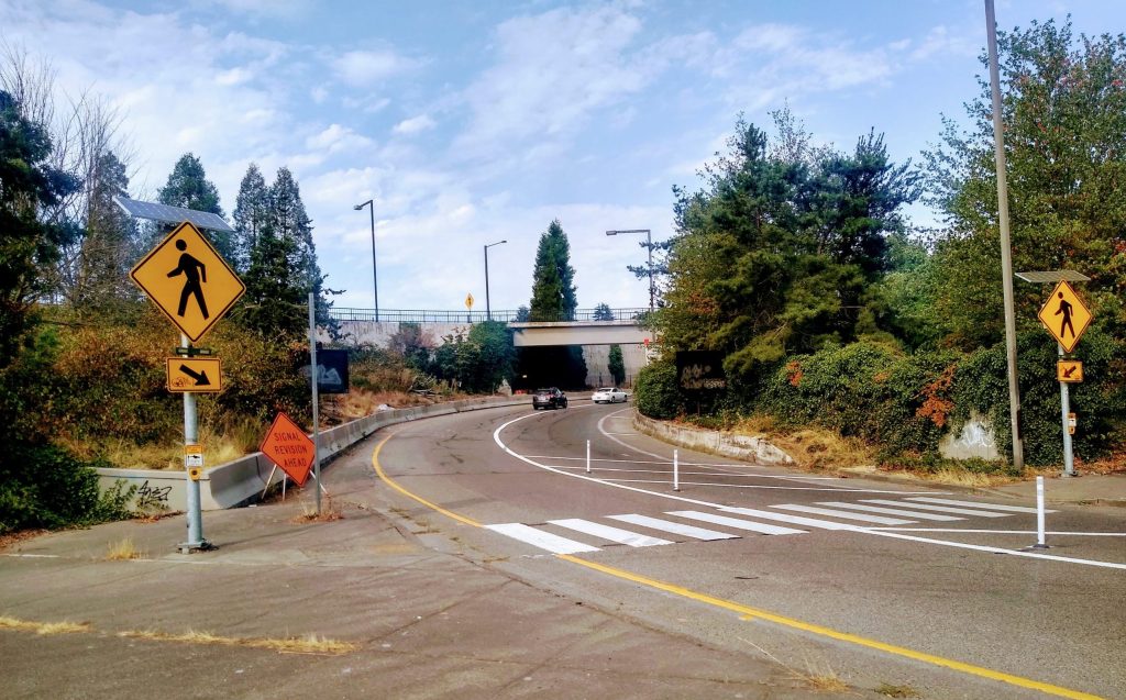 A highway ramp with vehicles entering I-90, with one lane marked off behind a few posts