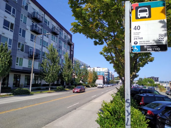 A bus stop along a four lane busy road reading 