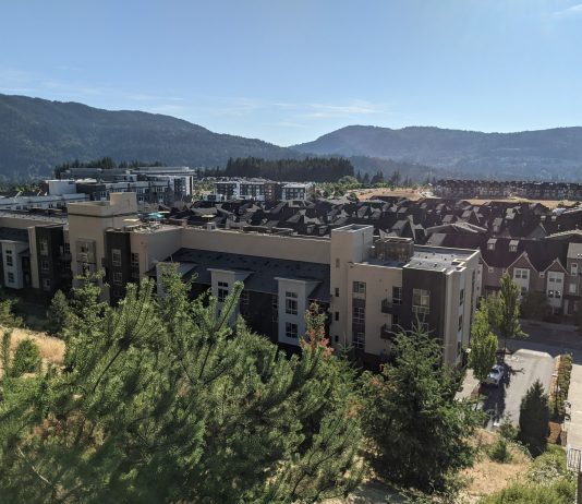 Fast Growing Issaquah Plans for More Density – and Sprawl A grouping of low-rise apartments and townhomes with trees and Issaquah foothills in the background.