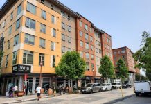 Social Housing Push Gaining Support as Housing Prices Skyrocket Image: A six story building with retail on the first level and pedestrians on the sidewalk.