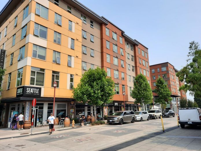 Image: A six story building with retail on the first level and pedestrians on the sidewalk.