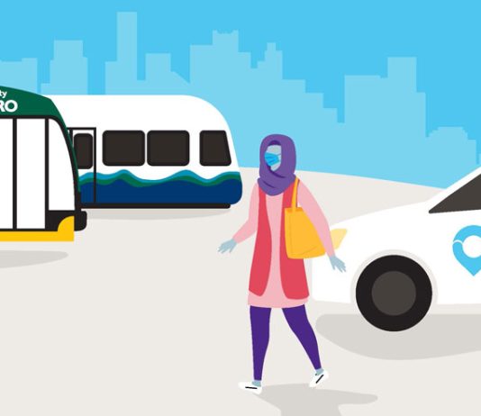 Metro’s Via To Transit Service Expanding to More Hubs, Adding Renton and Skyway A cartoon-style graphic shows a woman in a headscarf next to a Via van with a Metro bus and Link train in the background.