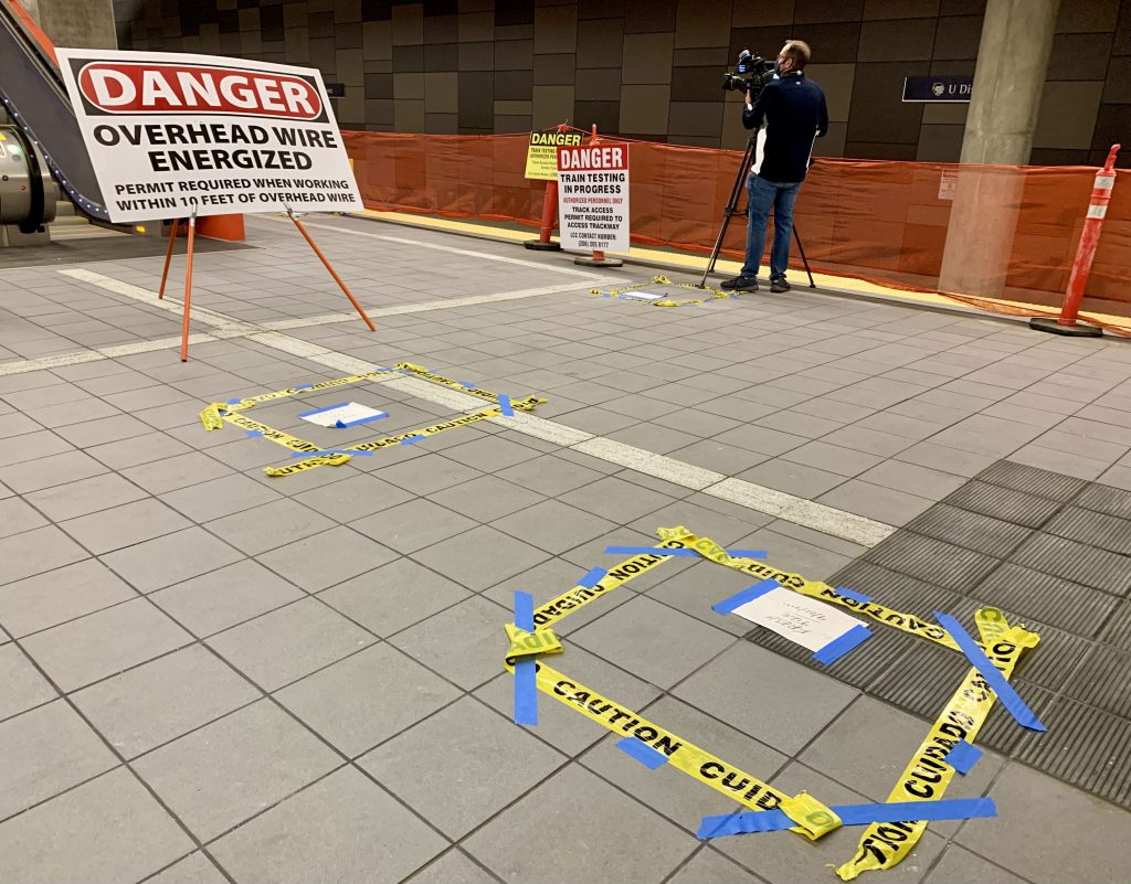 A photo shows a danger overhead wire  energized signs and caution tape installed on the station platform. 
