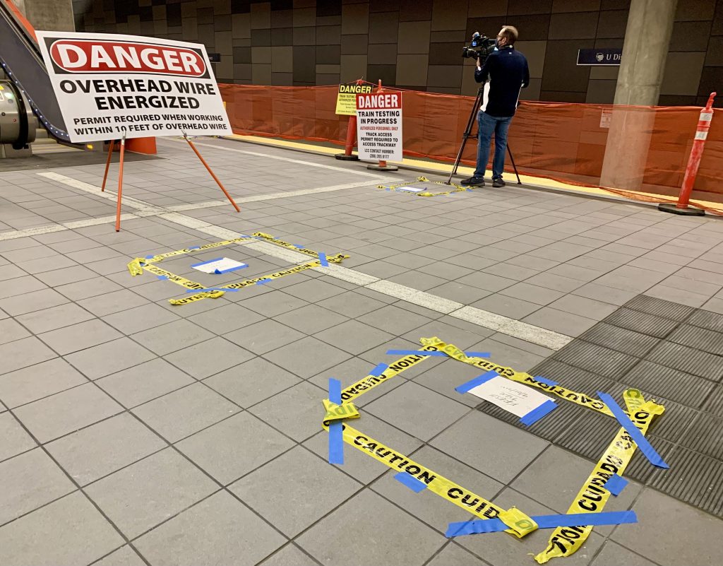 A photo shows a danger overhead wire energized signs and caution tape installed on the station platform.
