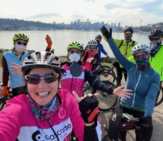 Events, Activities, and Advocacy for Urbanists, September 2021 A group of cyclists wearing colorful athletic clothes poses near their bicycles in front of Lake Union in Seattle.