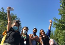 9 Steps for Addressing Seattle’s Homelessness Crisis Five women wearing face masks raise their arms triumphantly in the air. They are standing outside with a blue sky behind them.