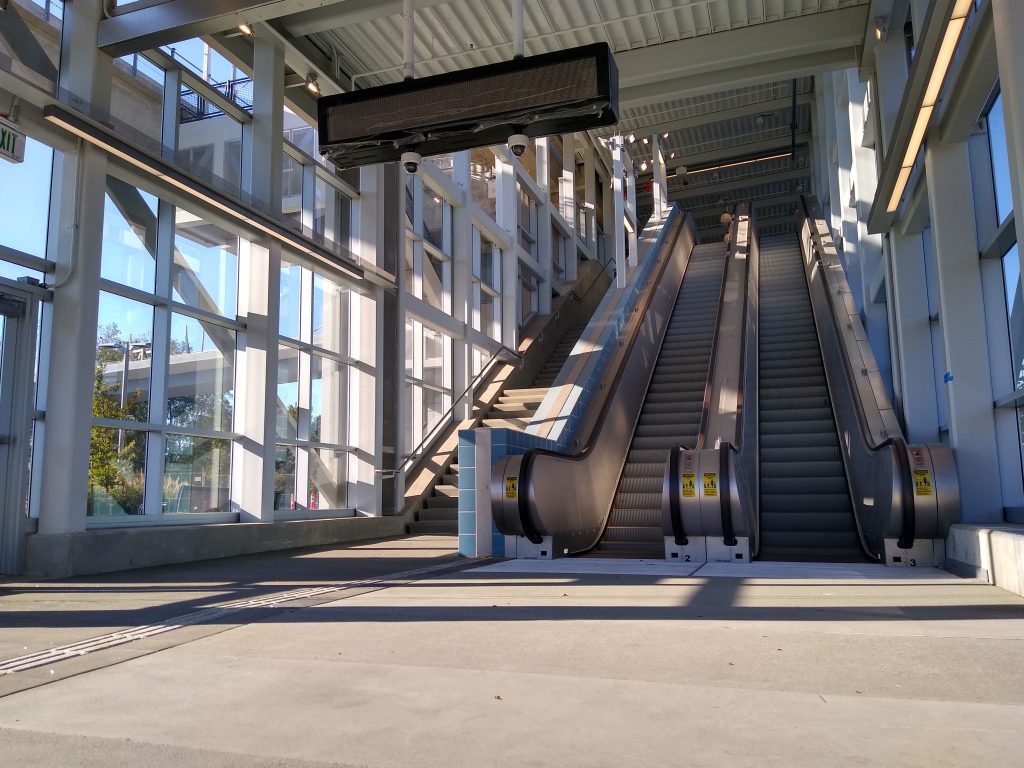 Two escalators and a stairway at a light rail station entrance