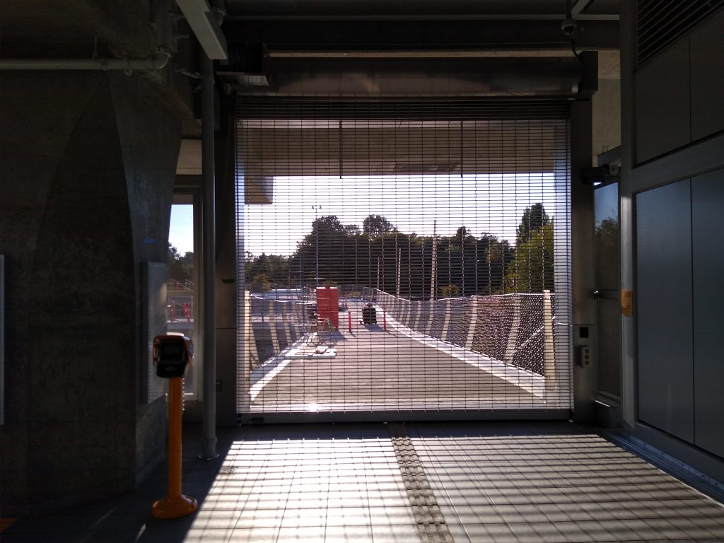 Metal gate with a pedestrian bridge beyond