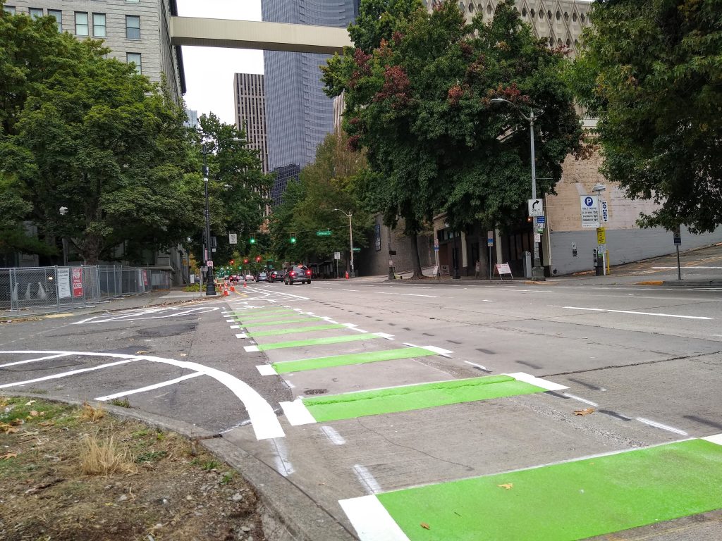 Wide green bars as street marking connecting with a protected bike lane