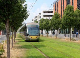 Envisioning a Car-Free Aurora Avenue A modern tram runs along grass in Nice with midrise building and trees flanking.