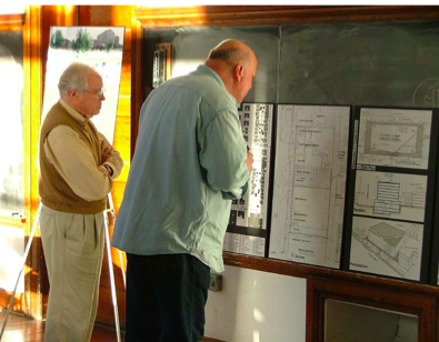 A photo of two senior men viewing a poster board, 