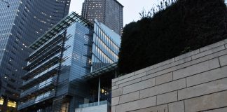 A photo of the Seattle City Hall with tall glass buildings illuminated at dusk in the background.