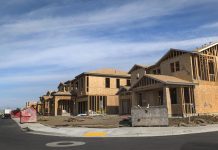 Goodbye Farmland, Hello Mega-Mansions The photograph shows a curved street of a large two story houses with garages under construction