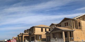 The photograph shows a curved street of a large two story houses with garages under construction