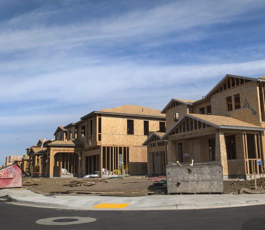 Goodbye Farmland, Hello Mega-Mansions The photograph shows a curved street of a large two story houses with garages under construction